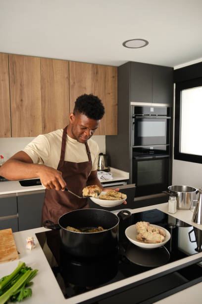 istock Young african man preparing fried chicken mince with vegetables recipe. 1495284072
