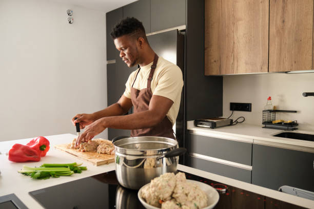Young black man preparing boiled chicken mince with vegetables recipe.