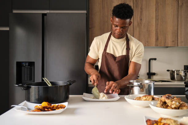 istock Young african man serving rice on a plate. 1495284732