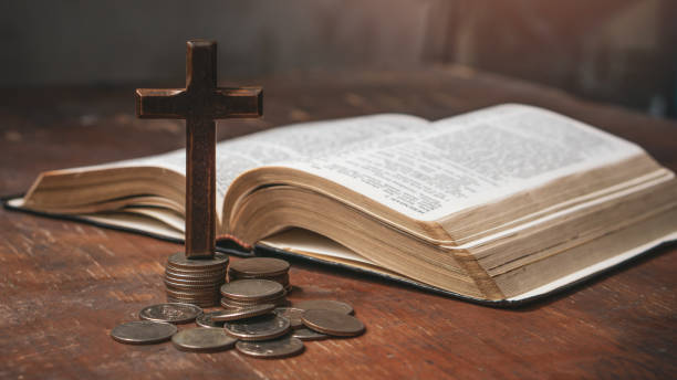 istock Tithe concept. Cross and coins with Holy Bible. Biblical concept of Christian offering, generosity, and giving tithes in church. 1495285278