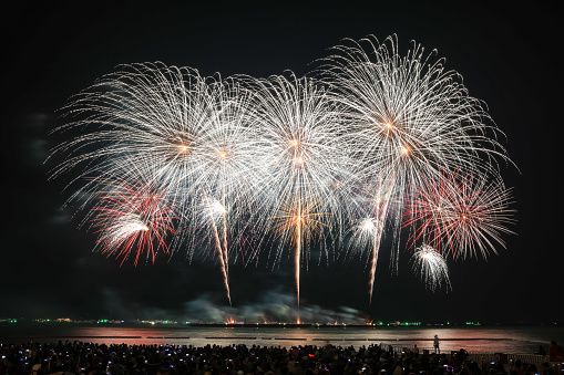 PATTAYA, THAILAND - NOVEMBER 25-26 : Beautiful lights at the night, colorful fireworks, and International fireworks at Pattaya International Fireworks Festival and small silhouette people tourist on the beach in front at Pattaya,Thailand. November 2021