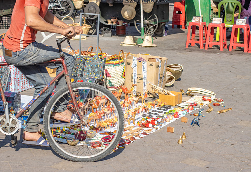 Souvenirs at Market Stall in Djemma el Fna Square in Marrakesh, Morocco, with a man cycling past.