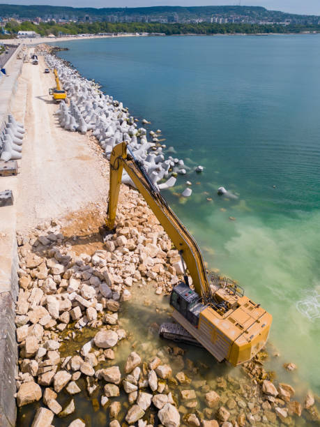 istock An excavator diligently constructs a dock or breakwater in the sea, its mighty arm reaching out from the shore, creating a resilient structure amidst the waves. Aerial view 1495290667