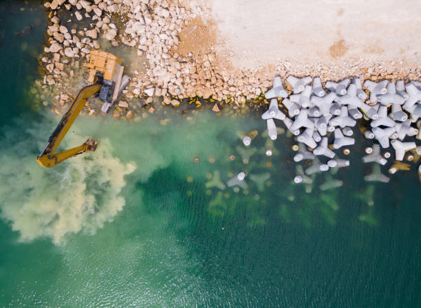 istock An excavator diligently constructs a dock or breakwater in the sea, its mighty arm reaching out from the shore, creating a resilient structure amidst the waves. Aerial view 1495290672