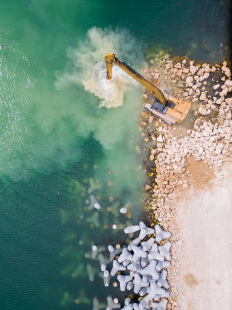 istock An excavator diligently constructs a dock or breakwater in the sea, its mighty arm reaching out from the shore, creating a resilient structure amidst the waves. Aerial view 1495290674