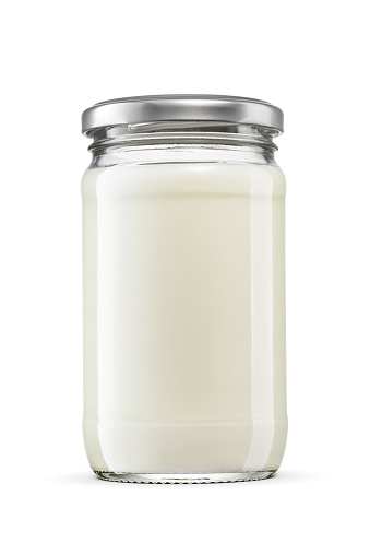 Mayonnaise sauce or dressing in glass jar on white background. Twist off metal screw lid, no label.