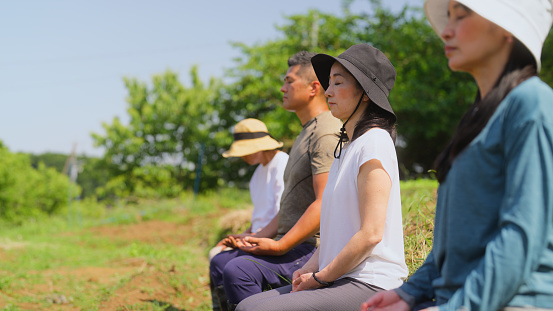 A group of family farmers and community are meditating before working on a farm filed.