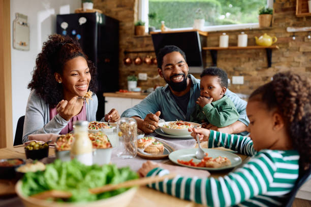 istock Happy black family talking while eating lunch together at dining table. 1495293801