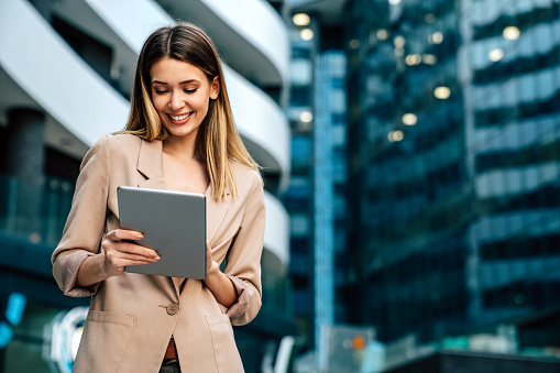 Portrait of young successful woman using digital tablet in urban background. Business people concept