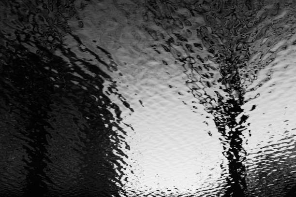 istock Abstract reflections of sky, trees and building on water with ripples 1495301126