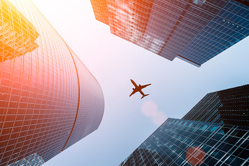 Airplane flying on business skyscrapers of financial center. Travel, economy, cargo, transportation concept