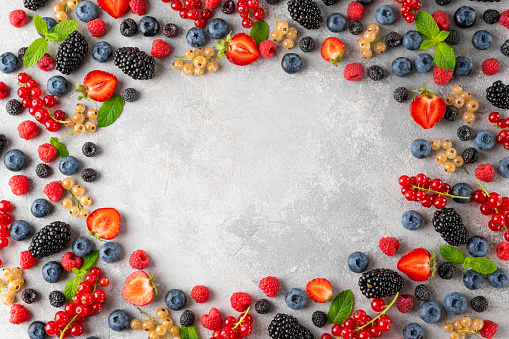 Various fresh summer berries on a gray concrete background. Healthy food concept. Top view. Food background