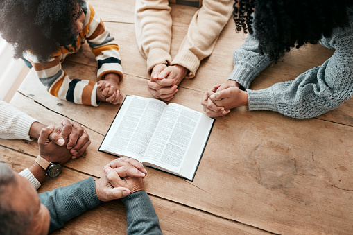 Bible, reading book or hands of family in prayer, support or hope in Christianity home for worship together. Mother, father or grandparents studying, praying or learning God in religion with children