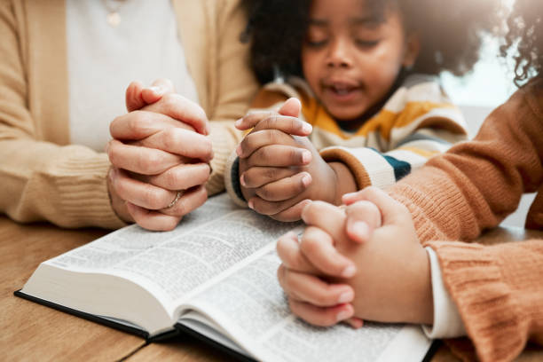 bibbia, mani o mamma che pregano con i fratelli dei bambini per la preghiera, il sostegno o la speranza insieme nel cristianesimo. educazione dei bambini, culto familiare o donna che studia, legge libri o impara dio nella religione - 4 of a kind foto e immagini stock