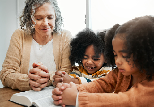 Bible, prayer or grandmother praying with kids or siblings for worship, support or hope in Christianity. Children education, family or old woman studying, reading book or learning God in religion