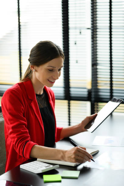 istock Attractive caucasian businesswoman using digital table and making important notes at working desk. 1495306351