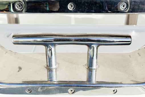 Stainless steel mooring bollard on the white hull of the yacht.