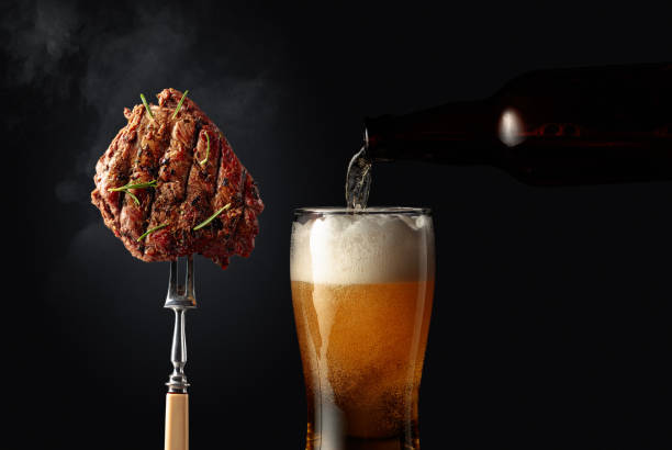 Grilled ribeye beef steak with rosemary and glass of beer. stock photo