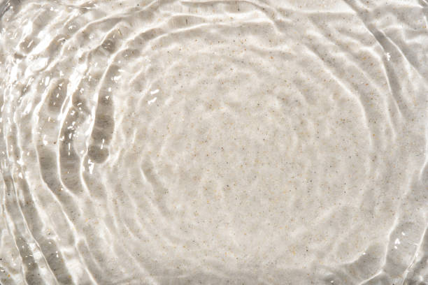 The texture of water on a sand background in bright sunlight.