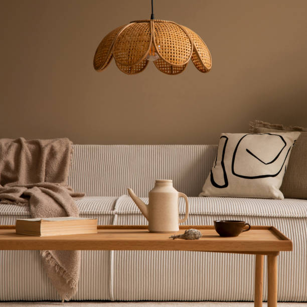 istock Warm and cozy living room interior with beige modular sofa, patterned pillow, brown plaid, wooden coffee table, books, stool, pitcher and personal accessories. Home decor. Template. 1495317969