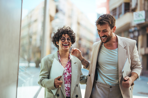 Business people discussing and smiling while walking together outdoor. Two Business Colleagues Having Discussion Whilst Walking Outside Office. Business people dressed in formal wear meeting in front of the office