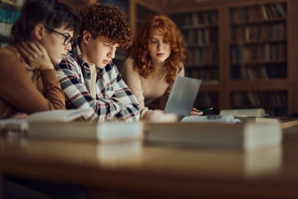 istock Group of teenage students using laptop in library. 1495320084