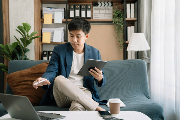 istock Businessman working at home with tablet and laptop computer and papers on desk. 1495320399