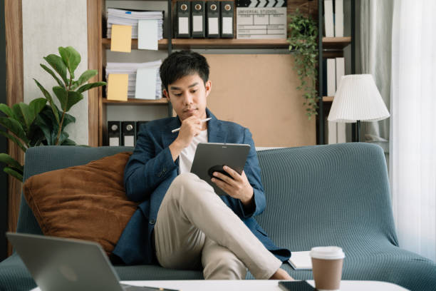 istock Businessman working at home with tablet and laptop computer and papers on desk. 1495320418