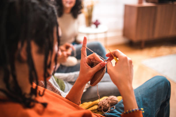 Young Mix Raced Siblings Learning Crocheting and Knitting Close-up of a teenage boy's hands holding woolen threads. A mix-raced boy crocheting and knitting with his family in the living room. knitting  stock pictures, royalty-free photos & images