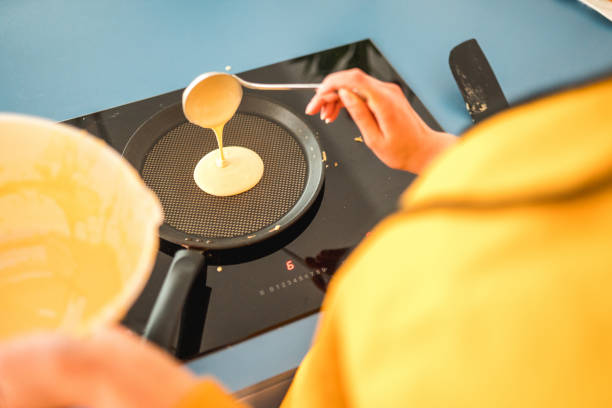 An unrecognizable woman making American pancakes for a family breakfast at home.