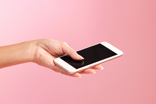 Phone mockup, hands and screen in studio isolated on a pink background. Cellphone, social media and woman with mobile smartphone for branding, advertising or marketing for product placement space.