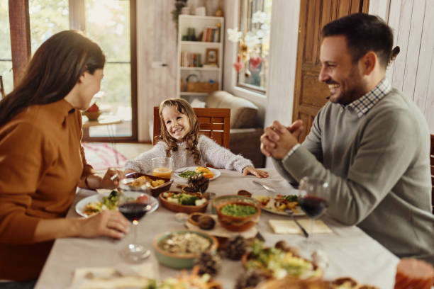istock Happy girl enjoying with her parents at dining table. 1495322444