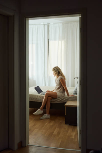 istock Young woman using laptop on a bed in bedroom. 1495324198
