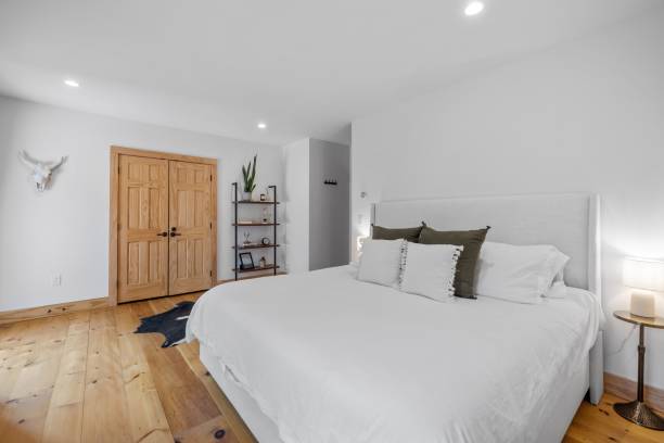 istock Cozy bedroom with a wood floor and a comfortable bed with white sheets and pillows 1495325035
