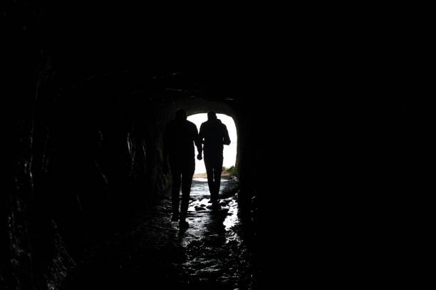 istock Silhouette of a man walking through a dark tunnel 1495325318