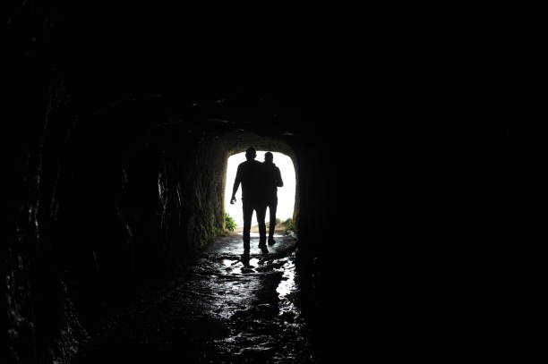 istock Silhouette of a man walking through a dark tunnel 1495325326