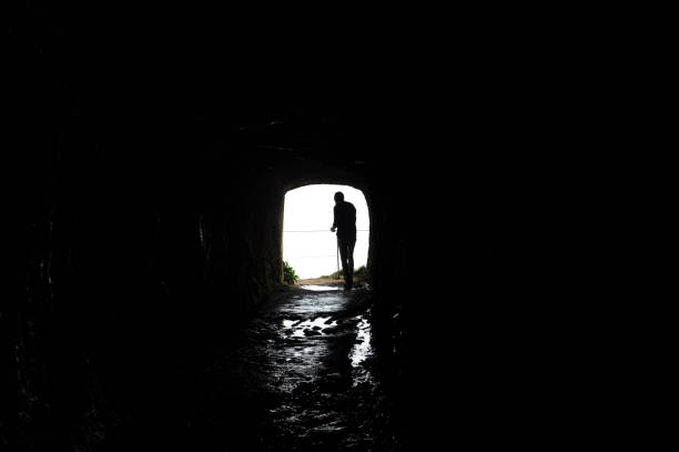 istock Silhouette of a man walking through a dark tunnel 1495325333