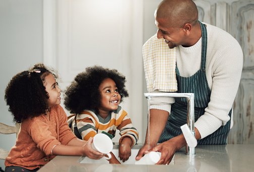 Cleaning, help and happy with black family in kitchen for bonding, hygiene or teaching. Smile, support and natural with father and children at home for sanitary, responsibility or housekeeping chores