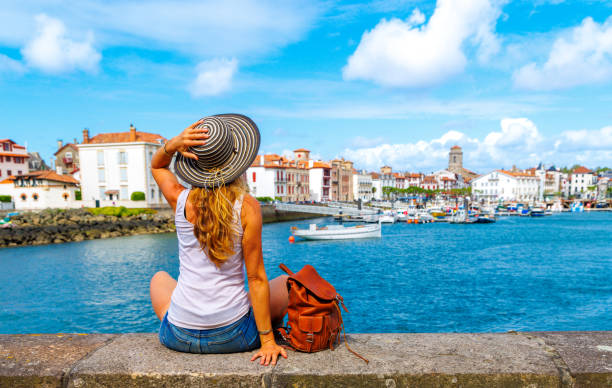 Traveler woman looking at Town of Saint Jean de Luz and fishing boat- Basque country near Biarritz in France- Nouvelle Aquitaine stock photo