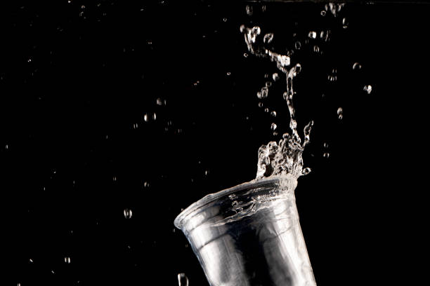 Glass with spilling water splash. Side view. On blue background. Clipping path included.