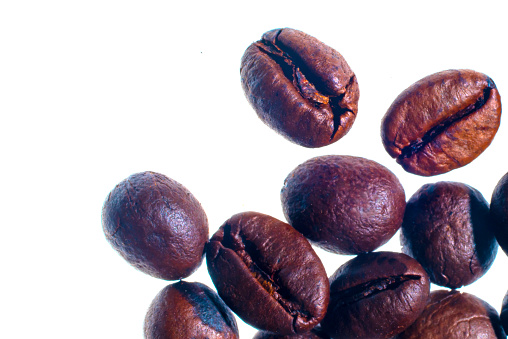 Organic coffee beans, freshly roasted, on a white background, selective focus, and soft focus.