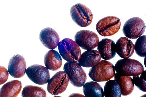 Organic coffee beans, freshly roasted, on a white background, selective focus, and soft focus.