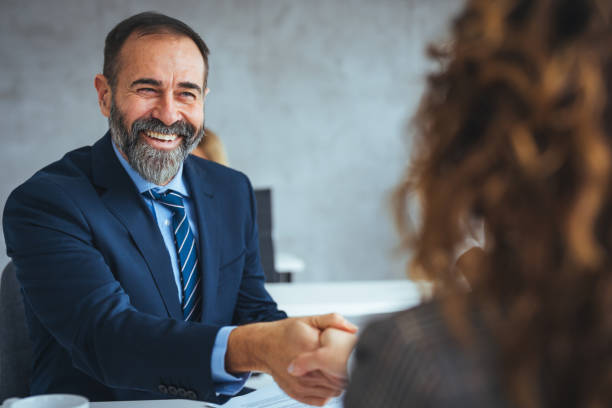 Happy senior entrepreneur came to an agreement with his colleague on a meeting in the office. stock photo