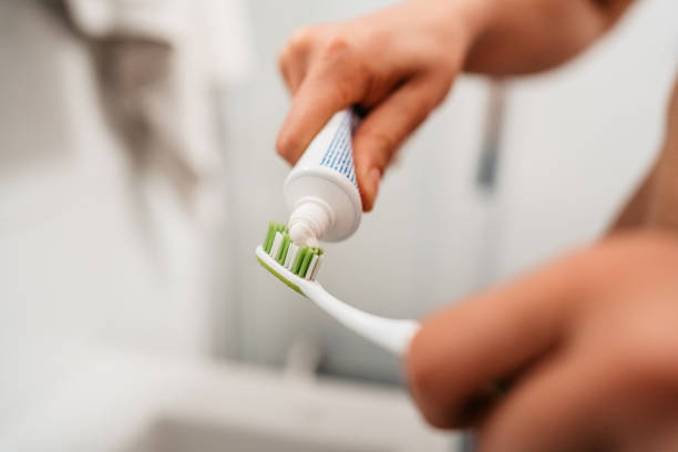 giovane che mette su dentifricio per lavarsi i denti in bagno - healthy lifestyle human teeth adult brushing foto e immagini stock