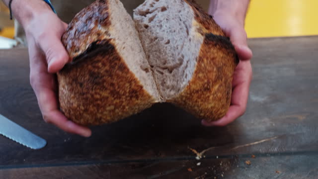 Baker Cutting a Loaf of Sourdough Bread in Half