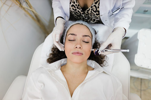 A young woman having a collagen induction treatment at the dermatologist's office
