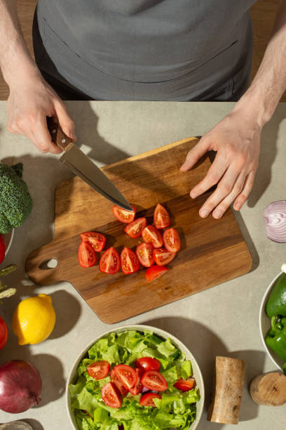 istock A man in a gray kitchen apron prepares a salad, close-up 1495346667