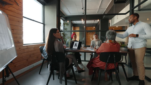 Collaborative meeting in a coworking office: Business ma having a discussion with his team in an office
