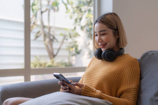 istock Attractive Asian woman resting comfortable living room and using mobile phone, Relax, Sofa, Lifestyle 1495347052