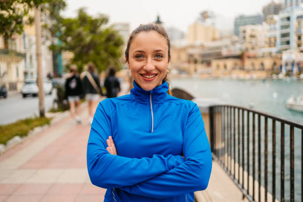 Young Woman In Sports Clothing On The Saint Julian's Promenade In Malta Portrait of a beautiful young woman in sports clothing standing on the Saint Julian's promenade in Malta. st julians bay stock pictures, royalty-free photos & images